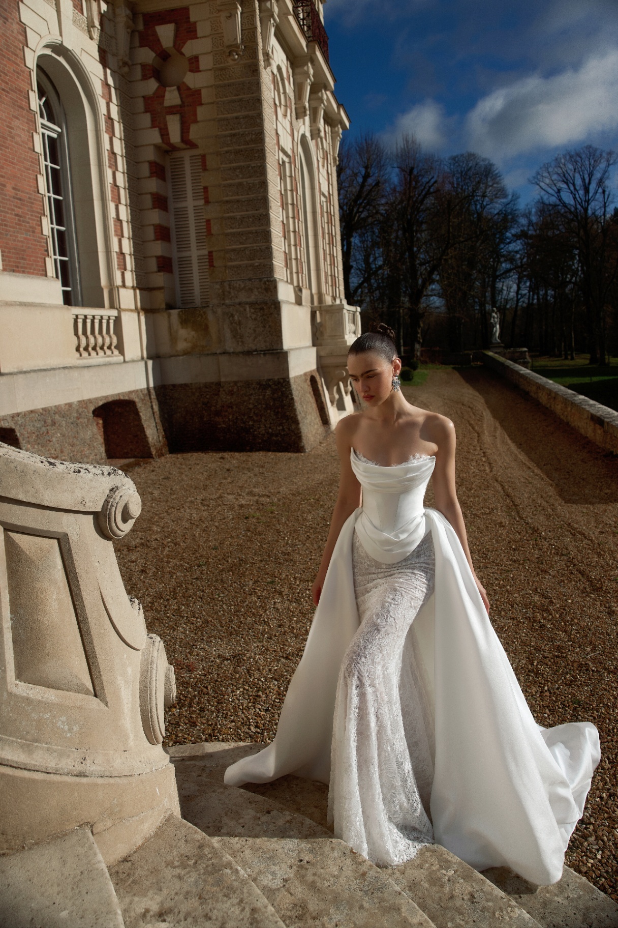Draped satin corset gown with overskirt on château steps